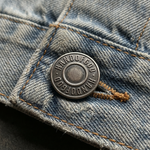 Close-up of a button on denim fabric with 'Wardrobe' branding.